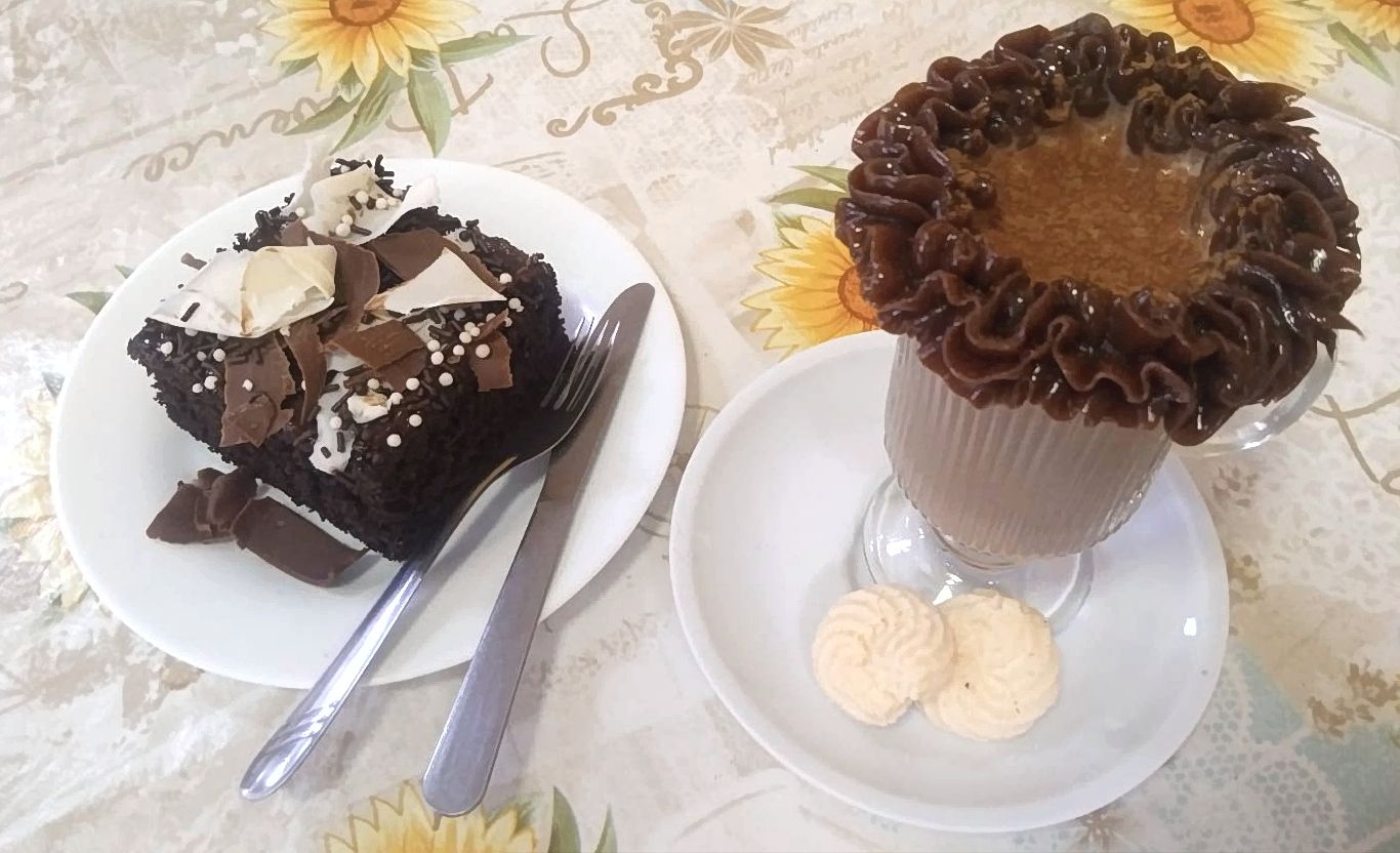 Bolo de chocolate e copo de café gelado com brigadeirão sobre a mesa
