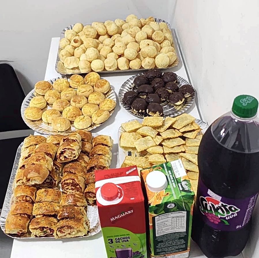 Mesa com pães de queijo, doces, enroladinhos e bebidas para reunião e confraternização